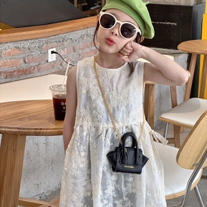 Mini sac pour enfants en cuir noir avec chaîne dorée porté par un enfant