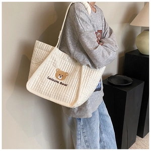 Detail view of quilted canvas tote bag featuring a cute bear print and shoulder strap