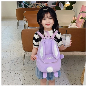 Detail of cute purple rabbit backpack with plush ears and tail shown on a young toddler