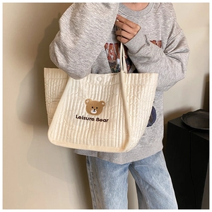 Detail of cute brown bear embroidery and Leisure Bear text on quilted canvas tote bag
