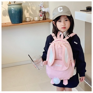 Detail view of pink rabbit backpack with fluffy tail and long ears worn by a child