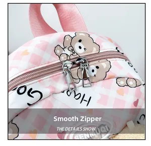 Détail d'un sac à dos enfant à carreaux roses avec fermeture éclair en métal et motif ours
