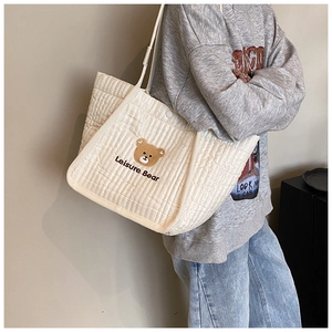Detail of embroidered brown bear and Leisure Bear text on quilted beige canvas tote bag