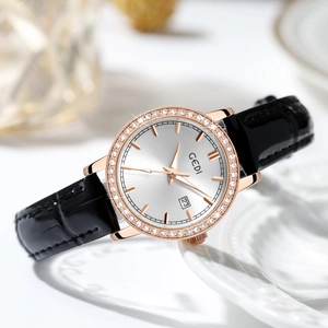 Women's rose gold luxury watch with diamond bezel, black leather strap, and calendar date
