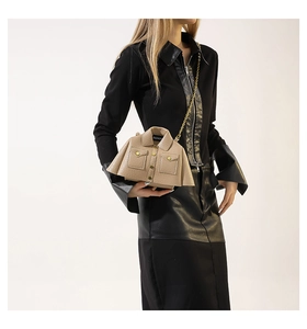 Detail of creative beige jacket-shaped crossbody bag with gold chain strap on model