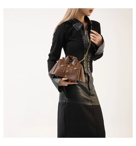 Detail of jacket-shaped brown leather bag with lychee texture and gold chain strap