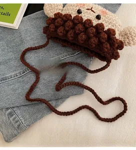 Détail d'un sac bandoulière tricoté pour enfant avec oreilles mignonnes et pompons 3D