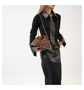 Detail shot of brown jacket-shaped crossbody bag with gold chain and lychee texture