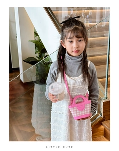 Close-up of pink checkered mini tote bag with leather strap on a child model