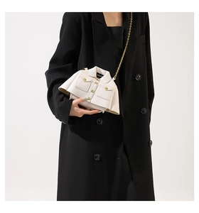 Detail showing white coat-shaped leather crossbody bag with gold chain and buttons