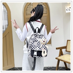 Détail du sac à dos scolaire à damier avec rabat noir et breloque ours en peluche