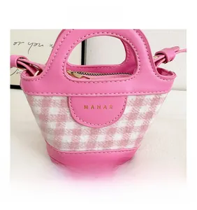 Close-up of a pink checkered mini handbag featuring golden hardware and leather strap