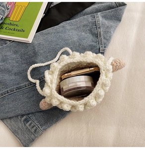 Détail d'une mini pochette blanche au crochet avec point pop-corn et maquillage