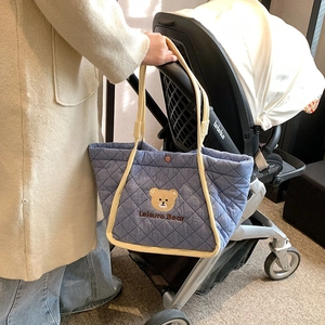 Quilted light blue canvas tote bag with cute bear embroidery hanging on a stroller