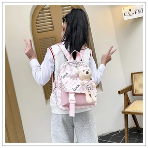 Détail du sac à dos en toile à carreaux roses avec un pendentif ours en peluche et boucle