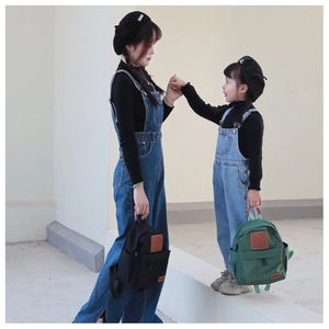 Outdoor shot of mother and daughter matching with mini nylon backpacks in dark blue and green