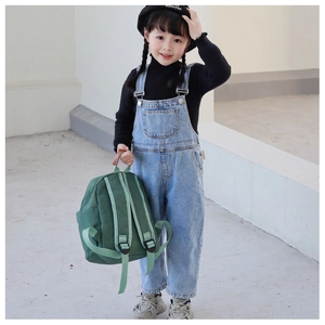 Toddler green canvas backpack styled with denim overalls for a trendy casual look