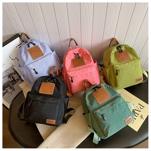 Detail view of colorful lightweight canvas backpacks with smiley patch and side pockets