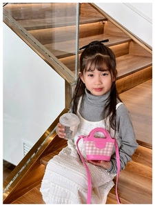 Detailed view of kids pink plaid mini handbag with HANAF logo on leather strap
