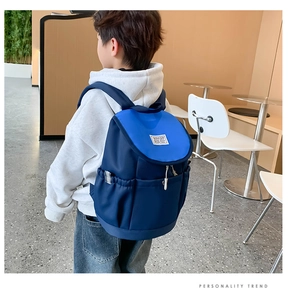 Detail view of stylish blue kids backpack with fashion label and drawstring side pockets