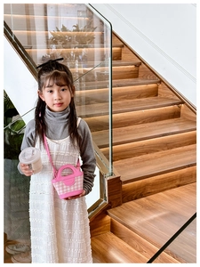 Pink and white checkered mini handbag with leather handle worn by a girl on stairs