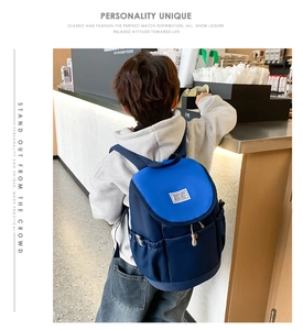 Detail of adjustable straps and side pocket on a two-tone blue nylon school backpack