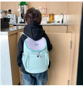 Close-up of mint green kids backpack with drawstrings and side pocket in a home setting