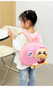 Pink cartoon dinosaur hard shell backpack shown on a child model in a bright setting