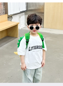 Detail of cute green dinosaur eggshell backpack with yellow tail on a child model