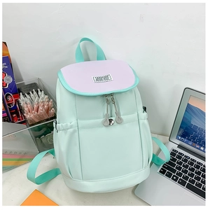 Detail of mint green nylon backpack with purple flap and fashion label on a desk