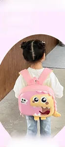 Pink and yellow cartoon dinosaur backpack shown on a child in a cozy nursery setting