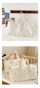 Close-up of quilted beige diaper bag with tulip and bear embroidery in a baby crib