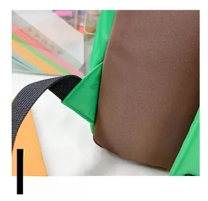 Close-up of triangle-reinforced stitching on green and brown nylon backpack straps
