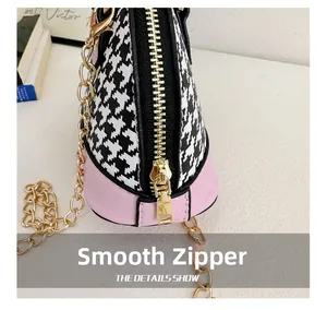 Detail showing smooth gold zipper on pink leather and houndstooth fabric bag