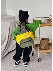 Vue de dos d'un enfant portant un sac à dos scolaire léger jaune et vert olive