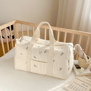 Quilted cotton diaper travel bag with olive embroidery in a cozy crib setting