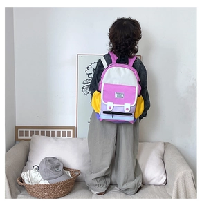 Detail view of colorful patchwork kid backpack with front pocket and round buckles