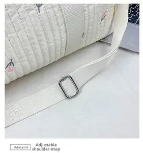 Detail of adjustable fabric shoulder strap with silver buckle on a quilted diaper bag