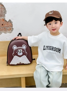 Dettaglio zaino rigido marrone per bambini con stampa orso e ali in pizzo bianco