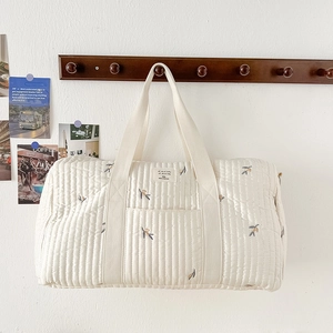 Quilted white cotton diaper bag with olive embroidery and top handles for travel
