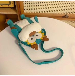 Détail d'un sac à bandoulière monstre bleu cyan avec des cornes en velours sur une table