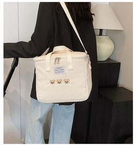 Detail of embroidered bear motifs and fashion label on off-white canvas diaper bag