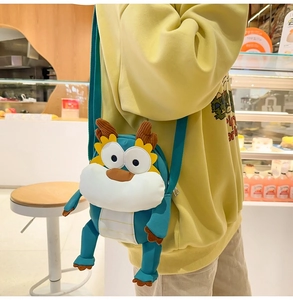 Détail du sac bandoulière dragon vert en peluche avec sangle réglable sur pull jaune
