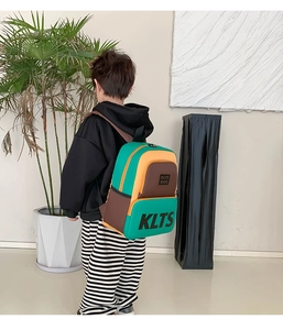 Rear view of kid's color-block backpack featuring green and orange panels with adjustable straps