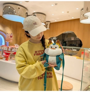 Gros plan d'un sac dragon en peluche verte avec bandoulière réglable dans une boulangerie