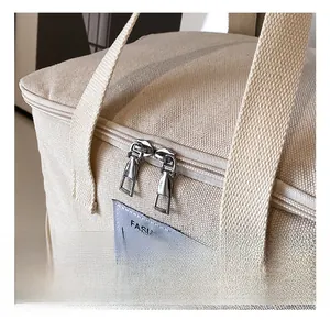 Macro view of beige canvas bag with embroidered bear and silver metal dual zippers