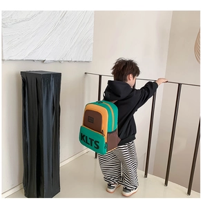 Boy wearing trendy color-block backpack with large KLTS letter print and side pockets