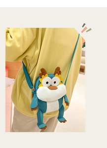 Détail d'un sac bandoulière en peluche dragon bleu avec sangle verte porté par un modèle