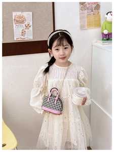 Girl wearing pink houndstooth shell handbag with gold chain strap in cozy home setting