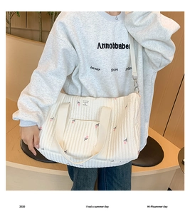 Detail of white quilted diaper bag featuring elegant pink tulip floral embroidery